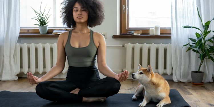 Woman Doing Yoga Beside her Dog