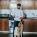 Black man standing with cup of coffee and croissant near Akita Inu