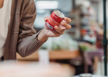 A Woman Wearing a Face Mask Holding a Canned Drink