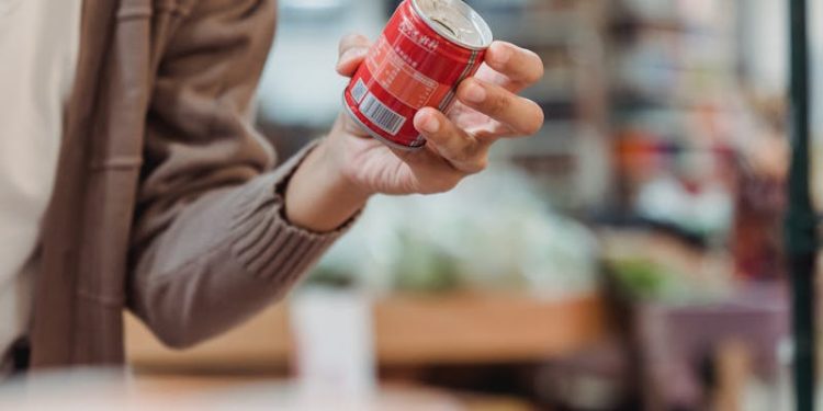 A Woman Wearing a Face Mask Holding a Canned Drink